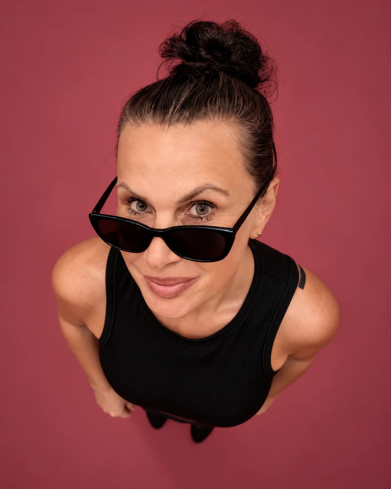 Sabina Kolba mit Sonnenbrille vor roséfarbenem Hintergrund